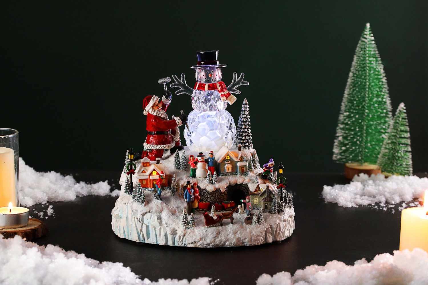 A charming Christmas village with a snowman and a beautifully adorned tree, all set in a snowy landscape.