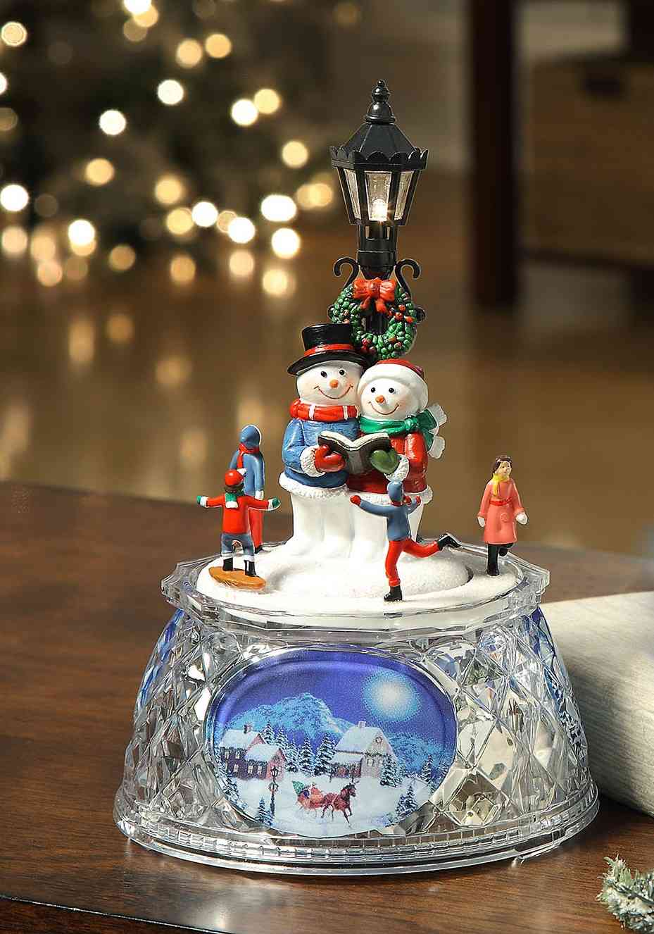 Three snowmen around a classic streetlamp—whimsical coastal Christmas village charm by A Coastal Christmas.