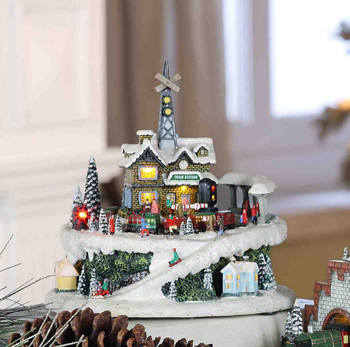 A vibrant Christmas village illuminated with lights, featuring a miniature train at the train station.